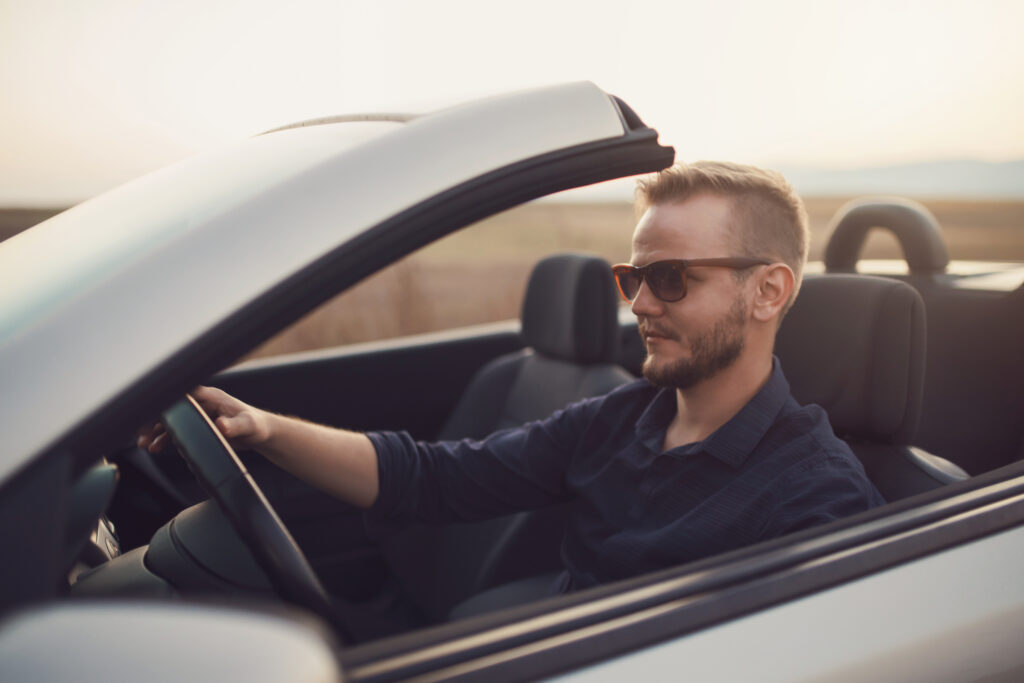 A man driving a convertible car